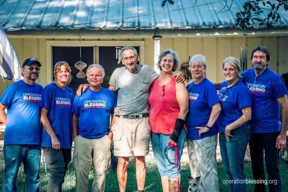 A team of disaster relief workers surround Brenda and Gerald as the blessings come back to them.
